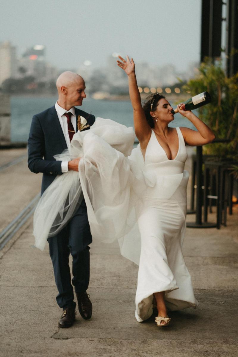 KWH bride and groom celebrating wedding with drinks in Sydney Harbour; Bride wearing AISHA gown by Karen Willis Holmes