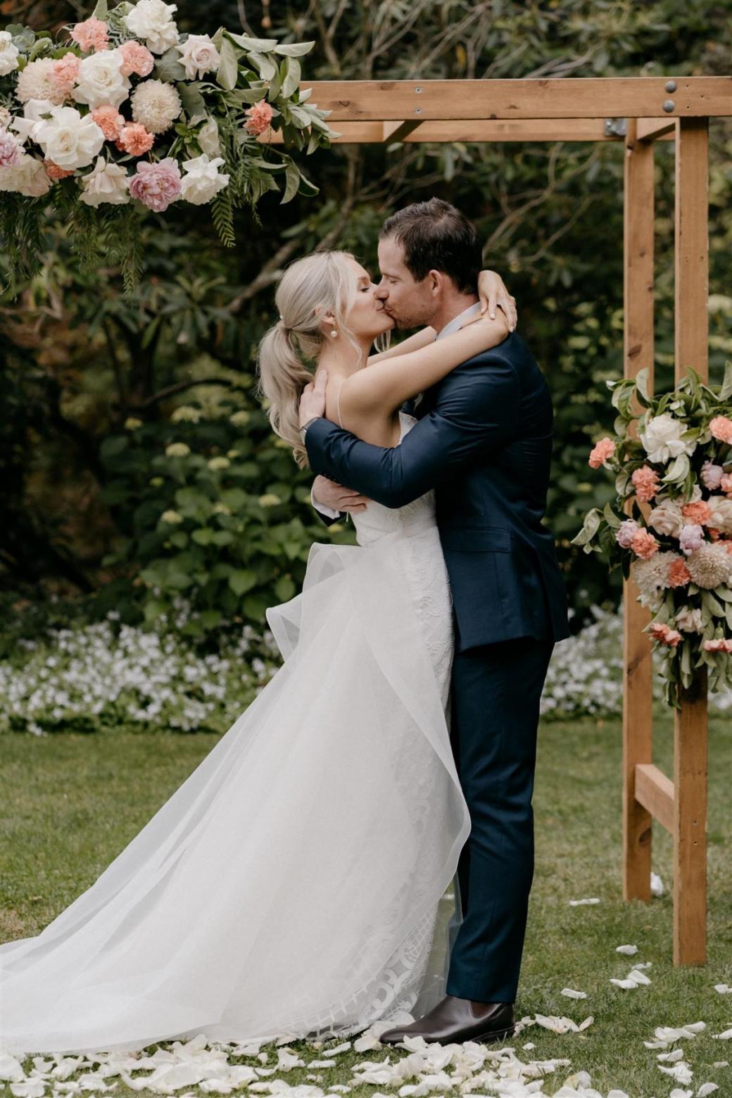 KWH bride Ashleigh and Adrian sharing a kiss at their country wedding; Ashleigh wears the dramatic Oval Trains with her Elodie gown by Karen Willis Holmes for ceremony look.