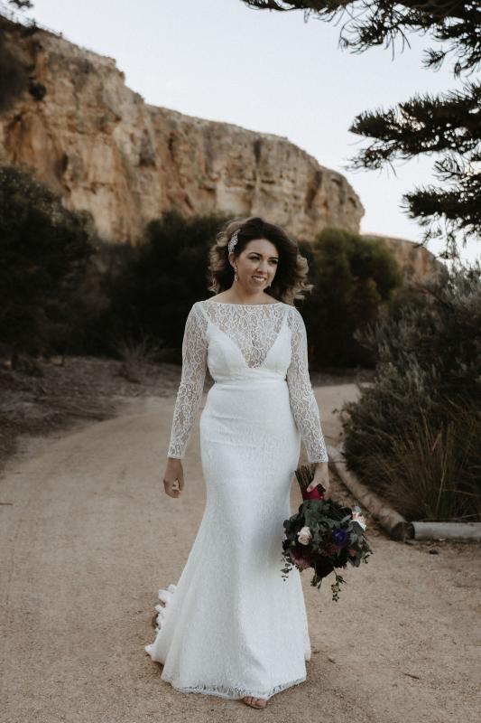 Karen Willis Holmes bride Meagan wearing the Karina gown; featuring a modern U-shaped plunging neckline with an illusion lace boat neck overlay and long fitted lace sleeves.