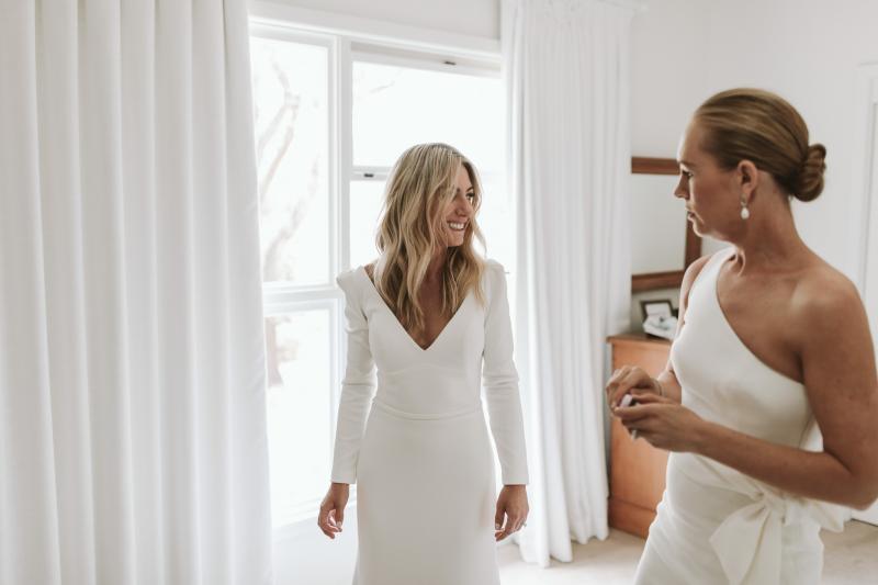 Real bride Annabelle getting ready for farm wedding wearing the Aubrey wedding dress by Karen Willis Holmes; a long sleeve minimalist wedding dress with a V-neck and long train.