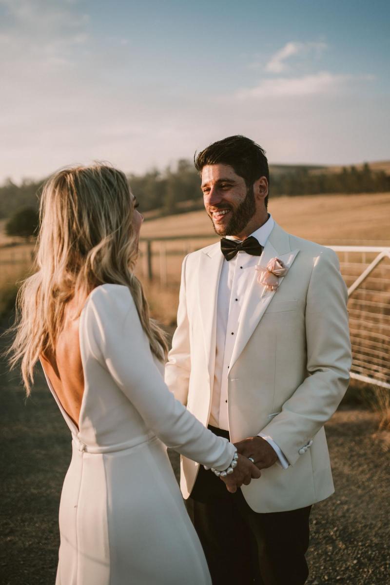 Real bride Annabelle with new husband at sunset on country family farm wedding; bride wears the long-sleeved Aubrey gown by Karen Willis Holmes.