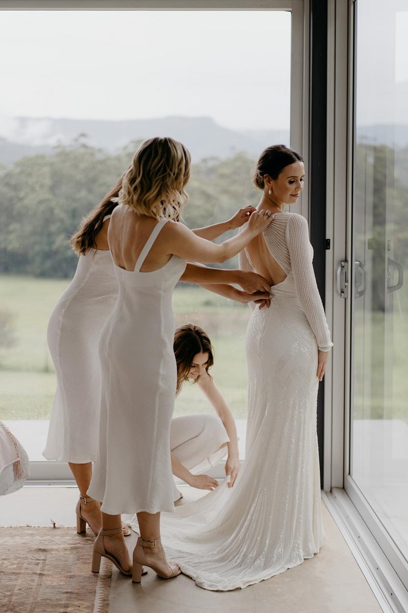 KWH bride Anna being dressed by her bridesmaids; wearing the Cassie gown with a long train.