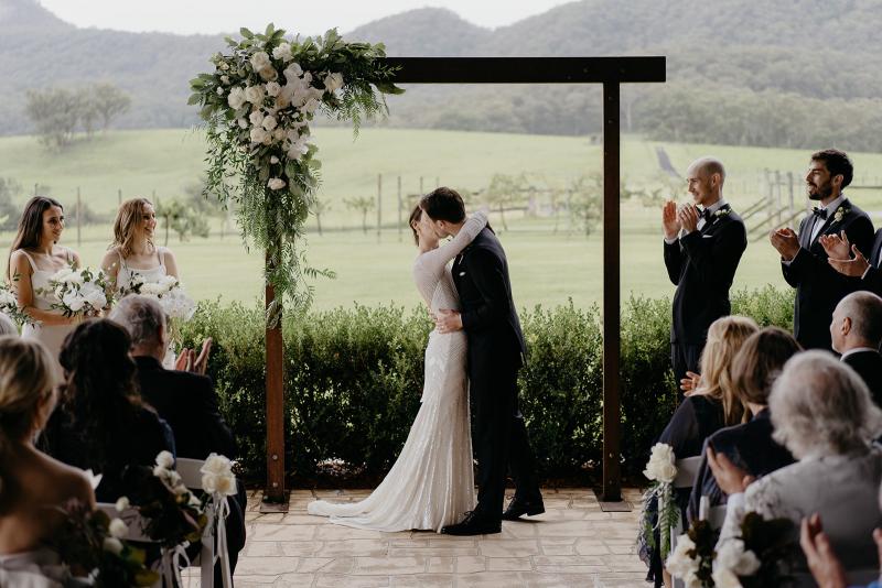 KWH bride Anna kissing her husband Julian under their arbour; wearing the Cassie wedding dress.