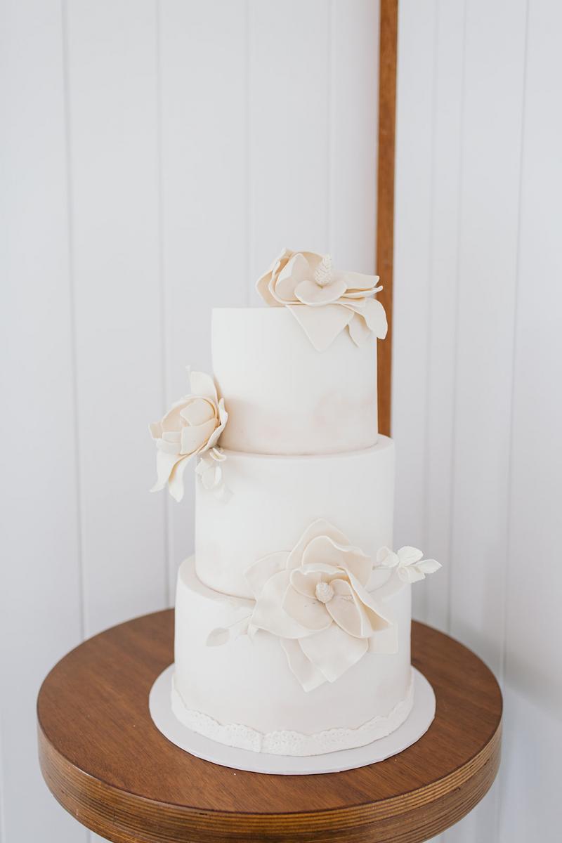 KWH bride Samantha's all white, three tiered wedding cake with two white flowers.