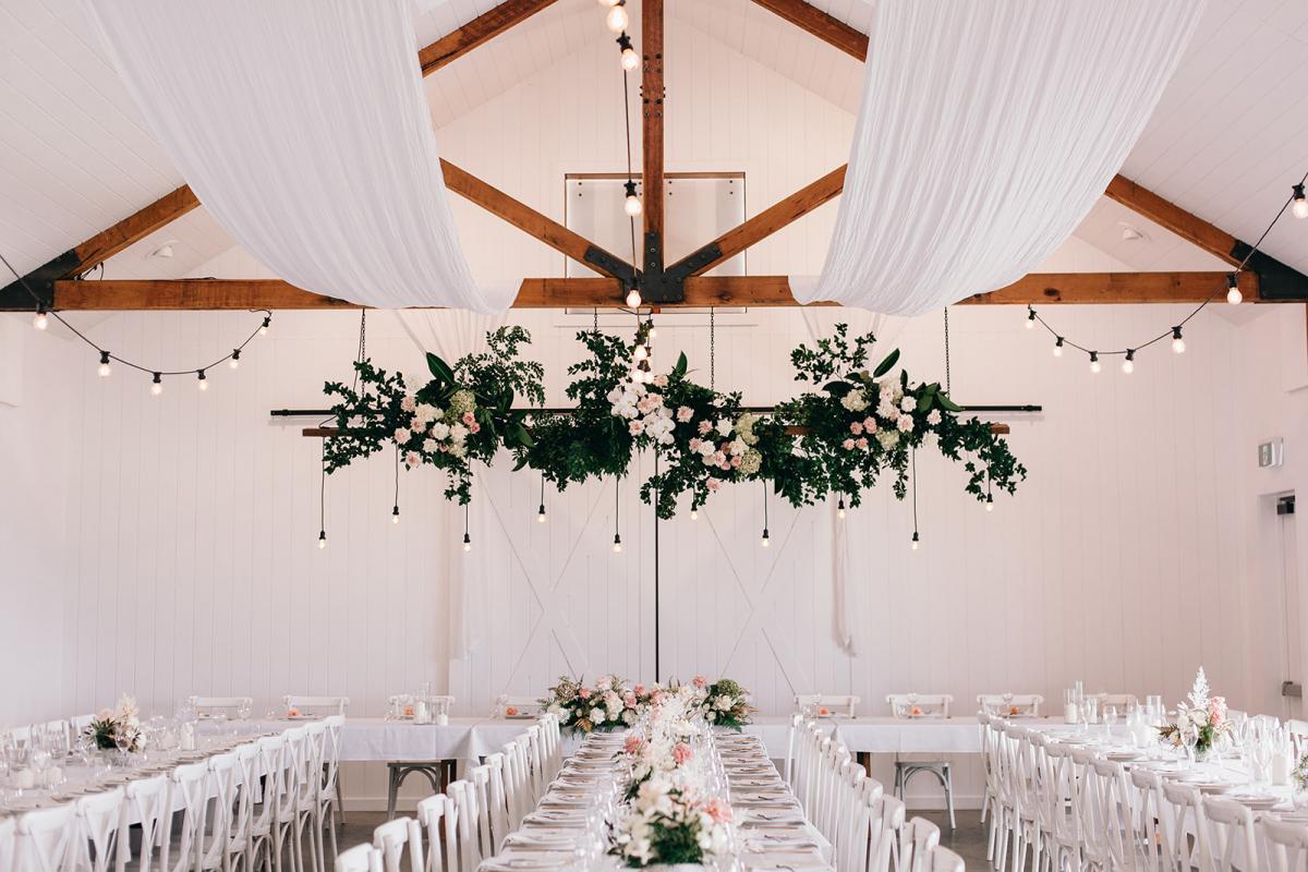 Rustic white reception hall with wood beams and hanging florals used for Real bride Samantha and Adam's hinterland wedding.