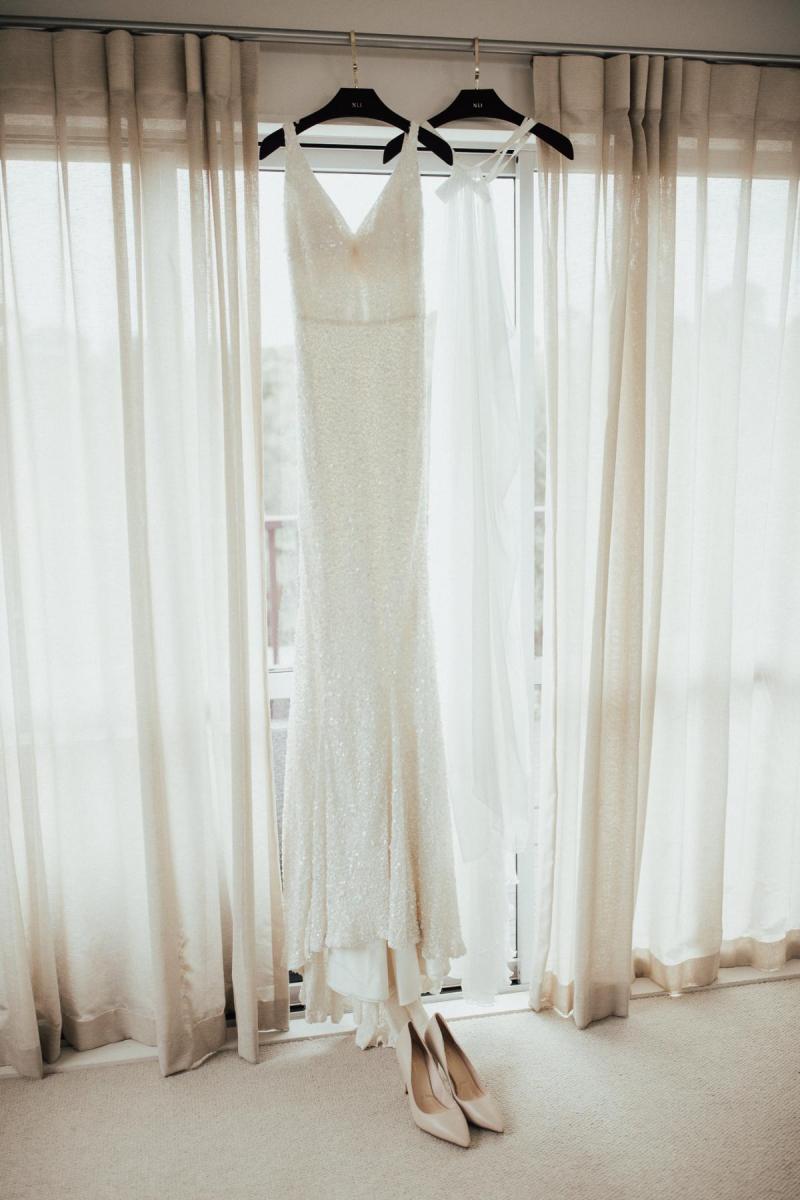 KWH bride Tash's Lola gown and Genevieve trains hanging in front of a window.