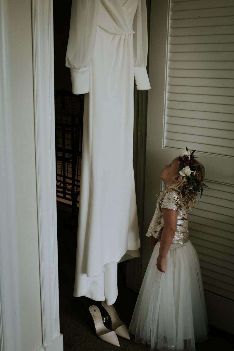 Real bride Lauren's flower girl looks up at Karen Willis Holmes dress, Nikki, hanging in the doorway.