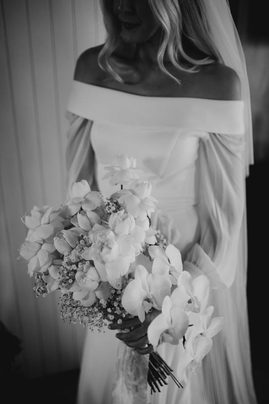 Real bride Hannah wears the long sleeve off shoulder wedding dress, Lauren with orchid bouquet