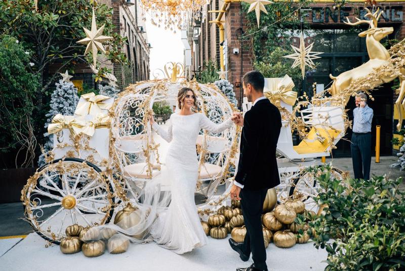 Real bride Katrina in front of Cinderella style carriage at the grounds of Alexandria, wearing the Margareta gown; a long sleeve backless wedding dress by Karen Willis Holmes