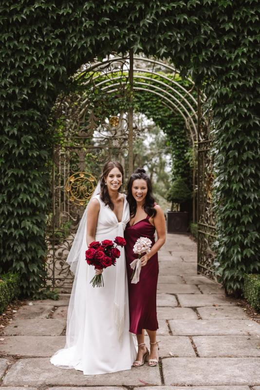Real bride April poses with her bridesmaids wearing red, bride wears the Arabella gown by Karen Willis Holmes with a red rose bouquet.