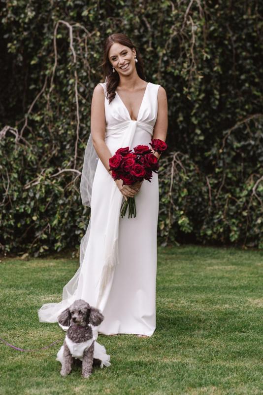 Real bride April wears the Arabella gown; a simple sheath wedding dress by Karen Willis Holmes with red roses bouquet.