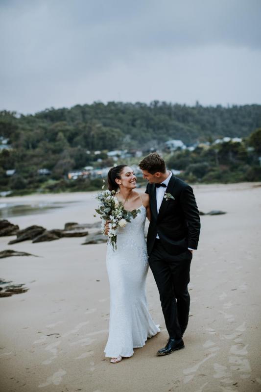 Looking smitten, Ruby and Taylor promenade on the beach as her Luxe Darcy gown by Karen Willis Holmes shines in the light..