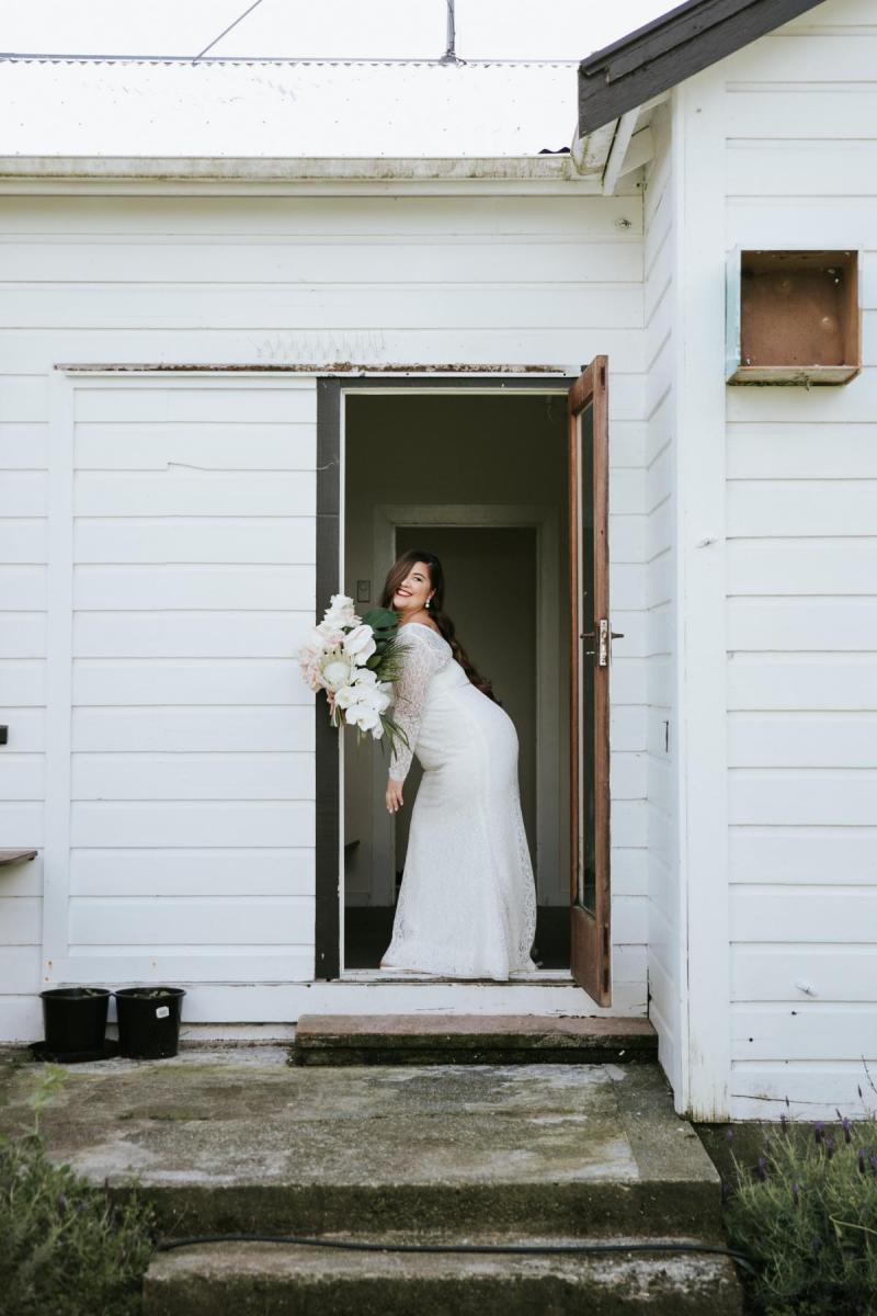 KWH bride Jarna pops a pose in the doorway of her rustic reception venue in Wellington wearing her Karina wedding dress.