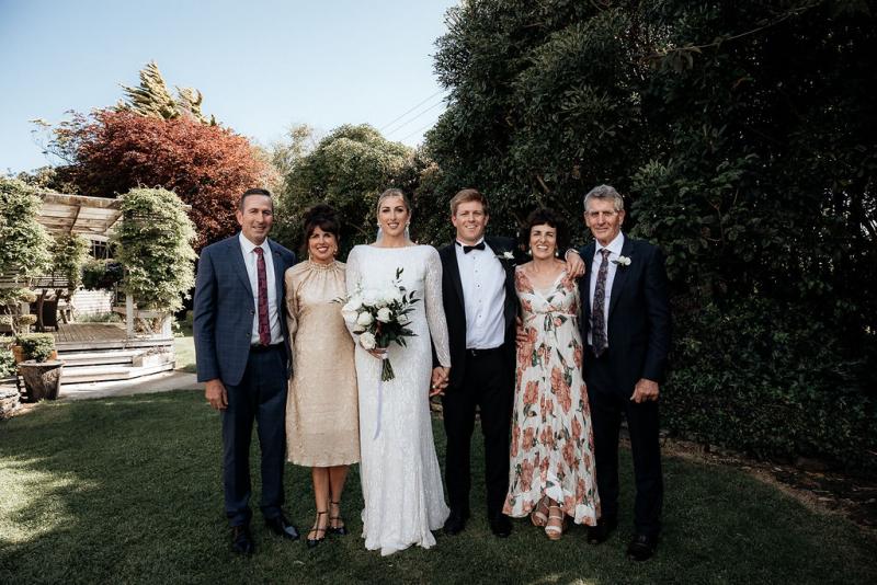 KWH Real bride Hannah and Angus stand with their family for wedding photos. The bride wears the long beaded Margareta gown.
