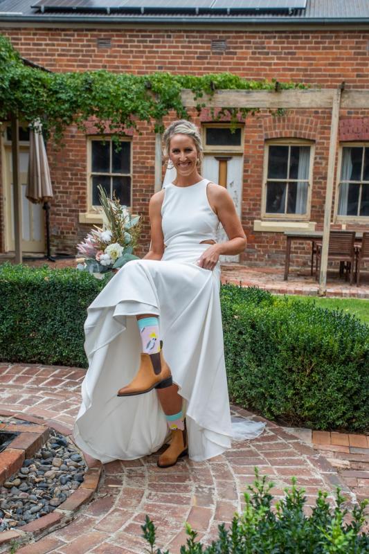 KWH real bride Angela shows off her country boots and ivory crepe Bridget gown with side cutouts.