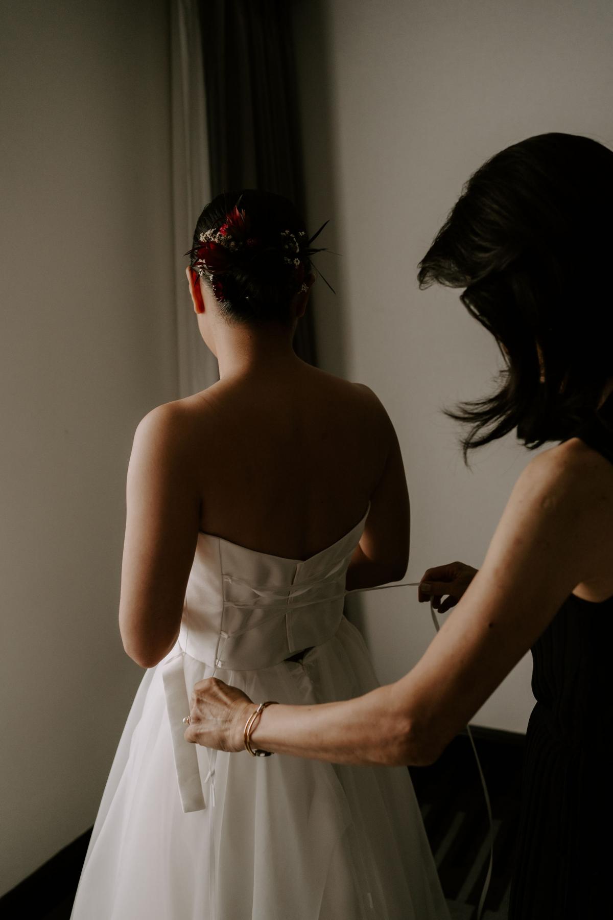 KWH real bride Sarah attaching her earring while wearing the Kitty Joni gown with twill and tulle fabrics.