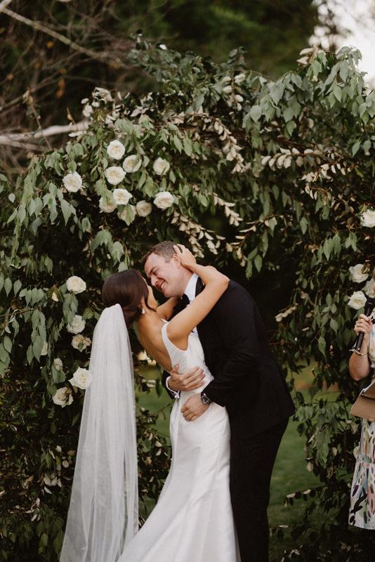 Real bride Charlotte and Myles have their first kiss. She wears the minimalist Leonie Alexia gown by KWH.