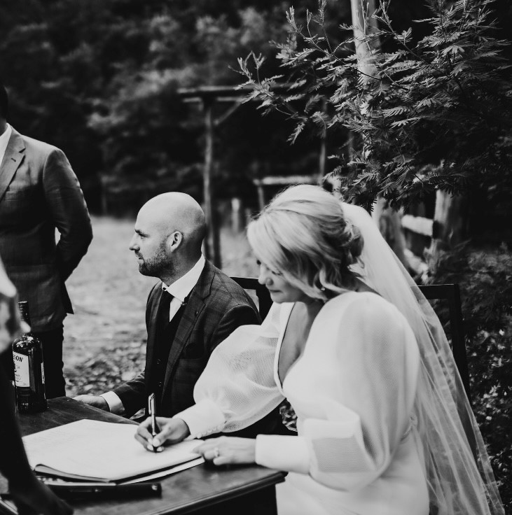 KWH real bride Caitlin signing the marriage docs with Eoin. She wears the modern Penelope wedding dress with mesh sleeves.