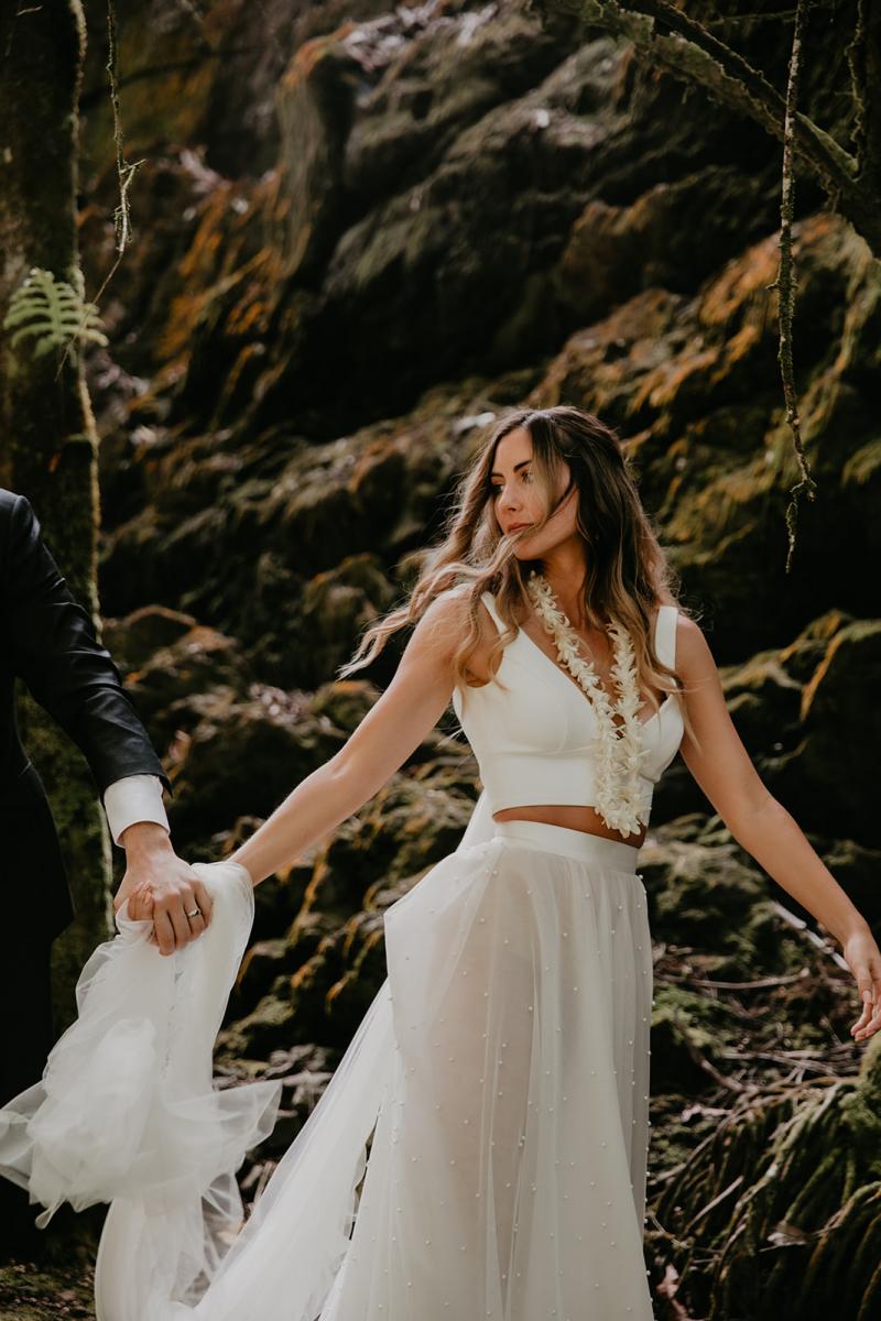 KWH real bride Jana walks with her new husband Garret through the rainforest in her sheer Lea skirt and cropped Erin bodice to her elopement.