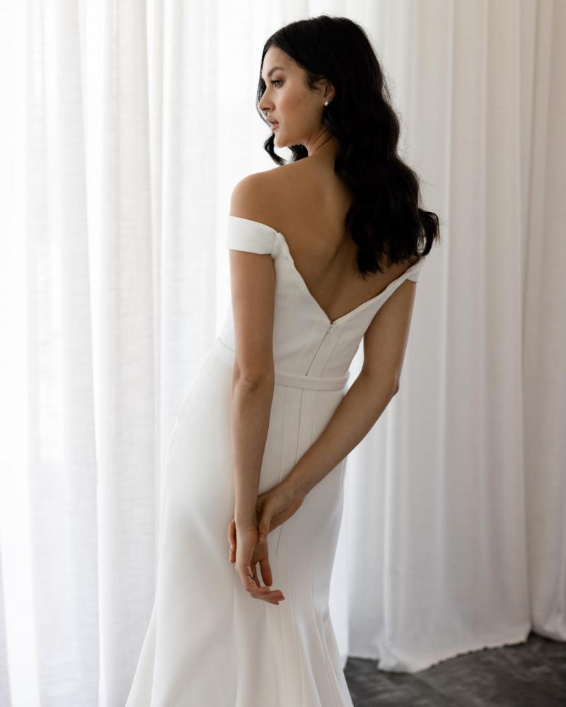 The Raven gown by Karen Willis Holmes, an off the shoulder fit and flare simple wedding dress. with belt and v-backline.