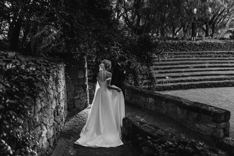 B&W image of KWH real bride Genevieve wearing her princess Blake Camille wedding dress with long train and button up back.