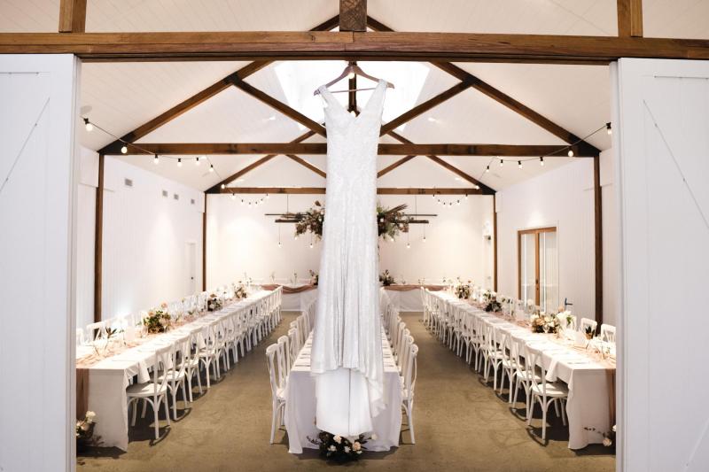 KWH real bride Georgie's Fontanne wedding dress hangs from the transom of their modern barn reception venue at Summergrove Estate.