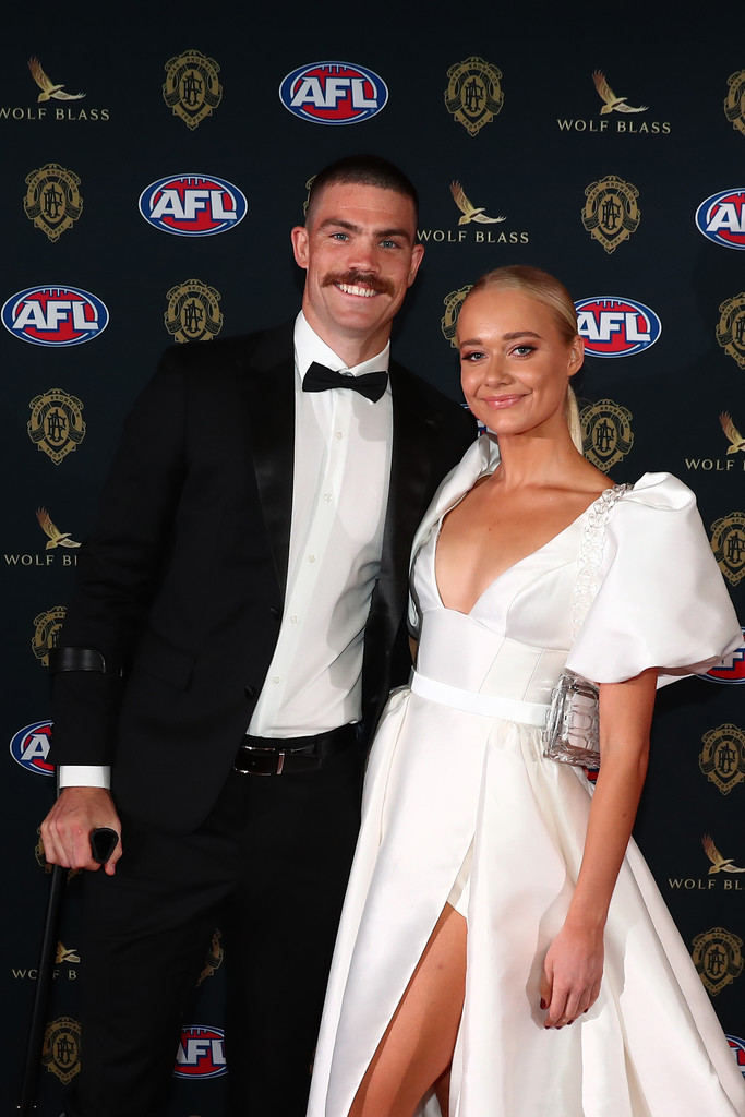 Georgie Mitchell poses on the red carpet with Sam Collins as she wears the Taryn Camille gown by KWH, nontraditional modern a-line wedding dress with slit.