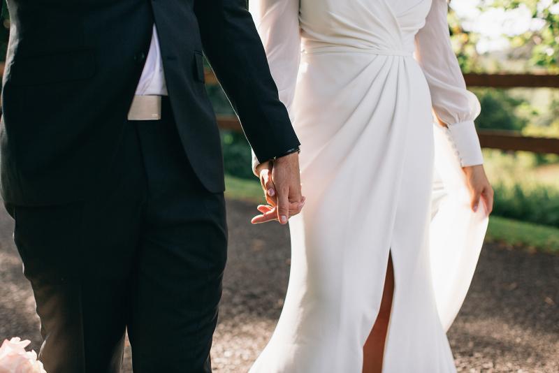 KWH real bride Rebekah and Joel walk holding hands. She wears the grecian inspired Nikki wedding dress.