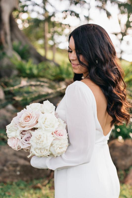 KWH real bride Rebekah stands with her pale bridal bouquet by Wren Floralista. She wears the stunning Nikki wedding dress with long sleeves and open back.
