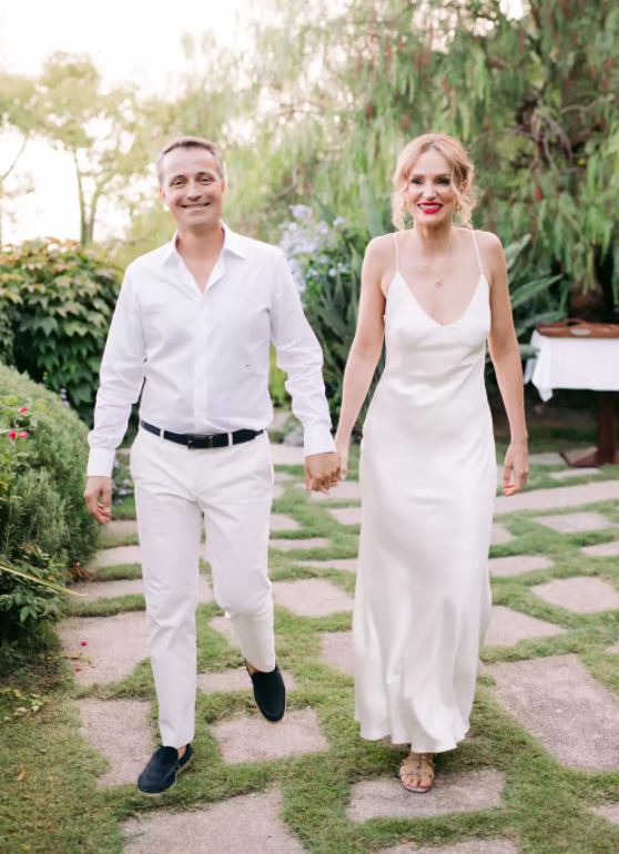 Danae Mercer stands with her Fiance in the gardens of the Amalfi coast in Italy. She wears the Sage gown, a modern silk slip wedding dress with V-neck.