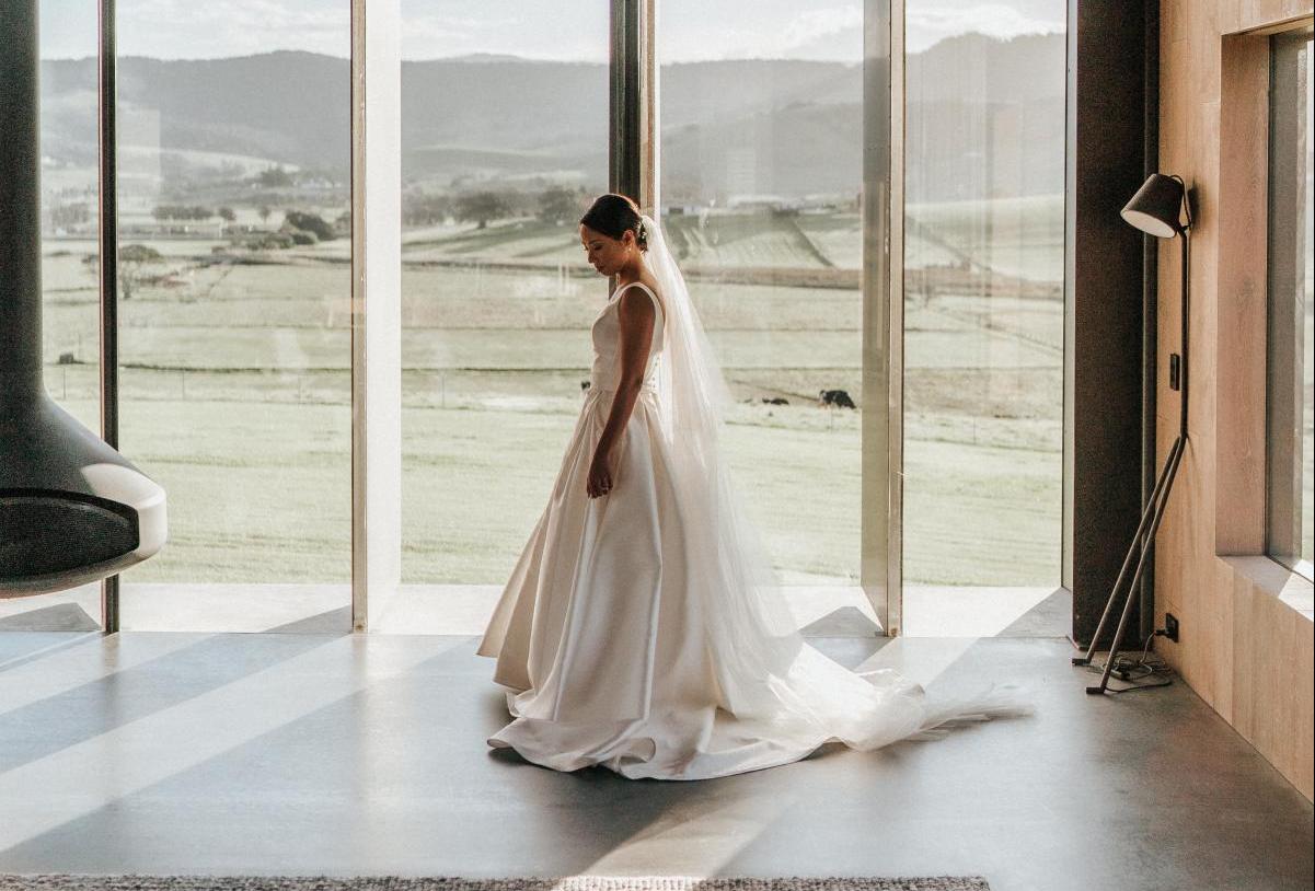 KWH real bride Rebecca stands in the transom of the modern building in her Leonie Melanie gown, a timeless a-line wedding dress with V-neck.