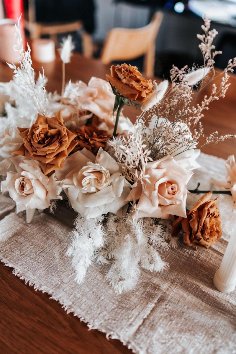 Burnt orange and light pink roses sit on the table at KWH real bride Rebecca's wedding.