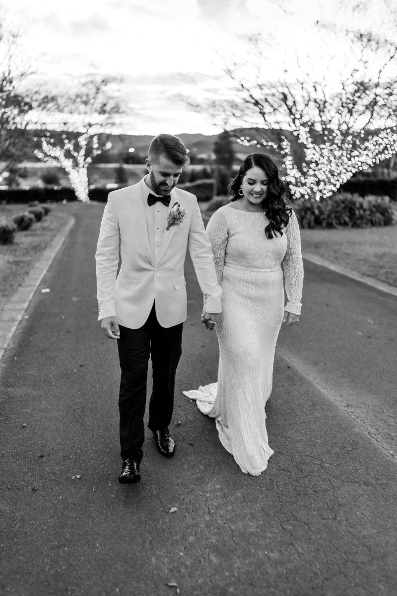 B&W image of KWH real bride Katherine and Conor walking in the street. She wears the beautiful Margareta gown, a long sleeve beaded wedding dress