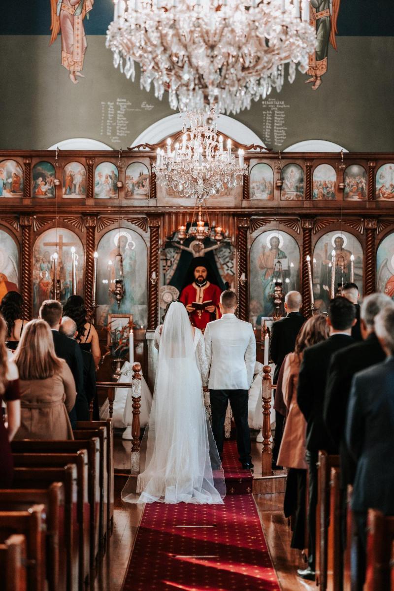 KWH real bride Katherine and Conor stand at their orthodox ceremony. She wears the alluring Margareta, long sleeve beaded wedding dress