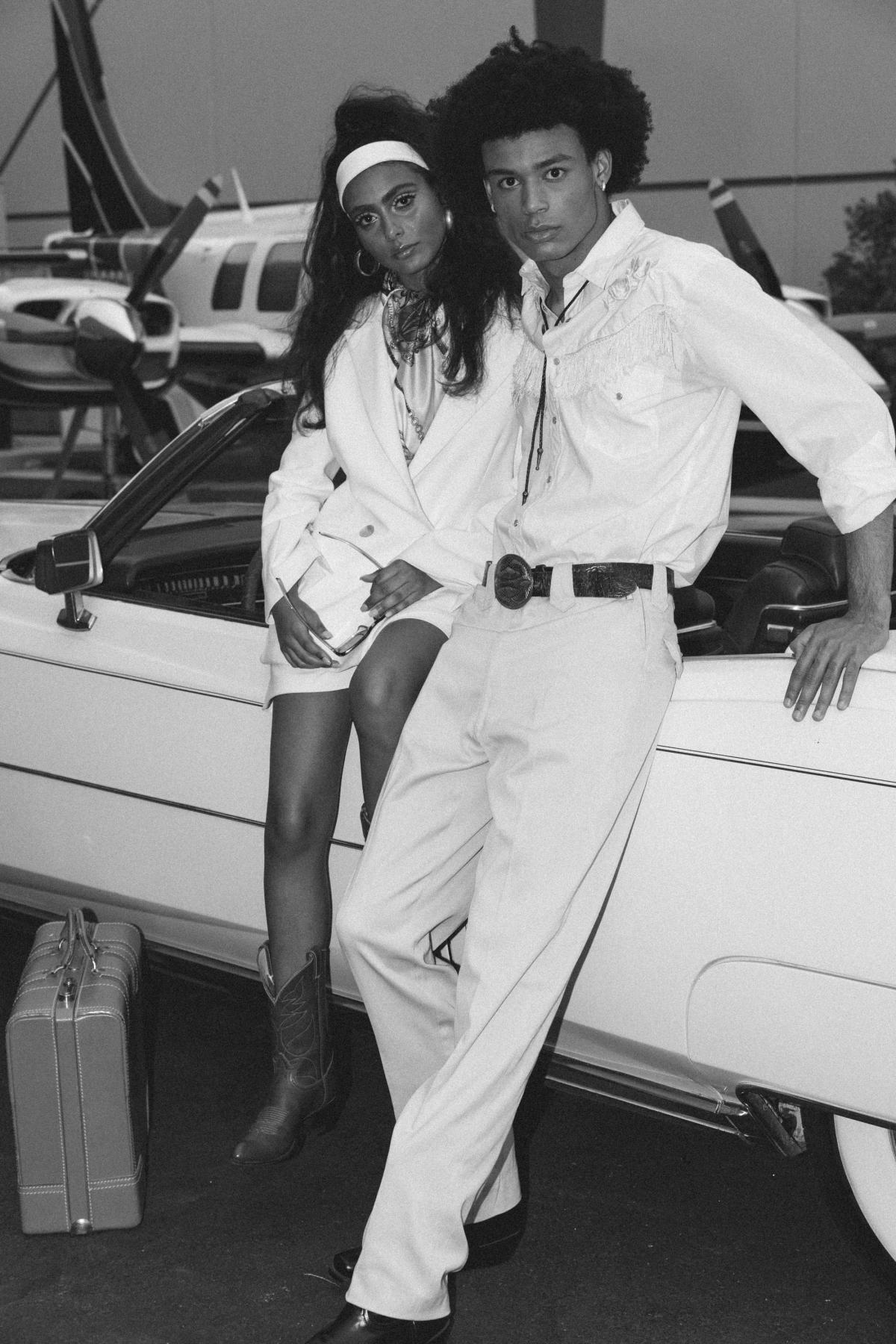 Couple posing by convertible El Dorado wedding car wearing a Karen Willis Holmes bridal suit, the Charlie Jacket and Dani short for a Las Vegas Elopement