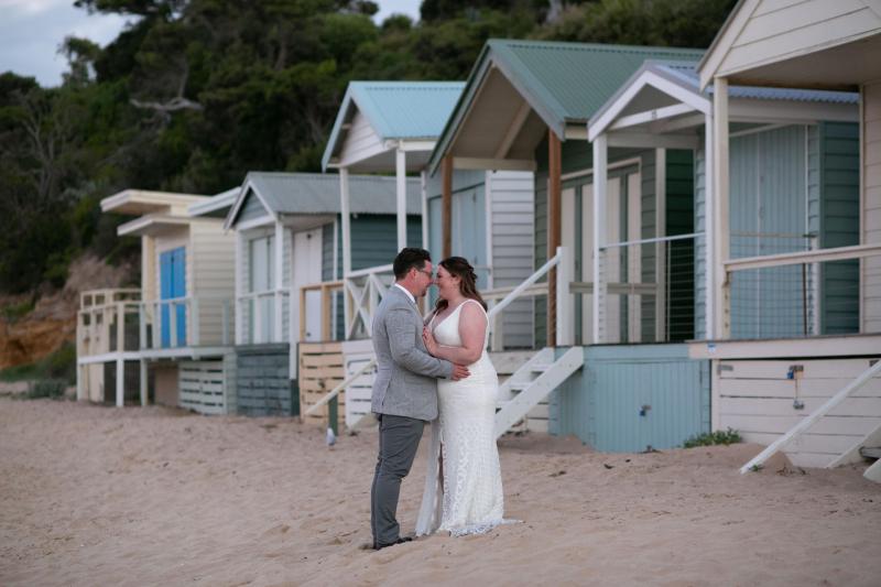 KWH real bride Meg kisses Tom by the beach houses in her Bobby gown, a modern fit and flare wedding dress.