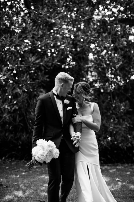 Newlyweds, Emily and Dan, snuggle up to each other in front of the foliage. Real Bride Emily wears the contemporary Violet gown by KWH.