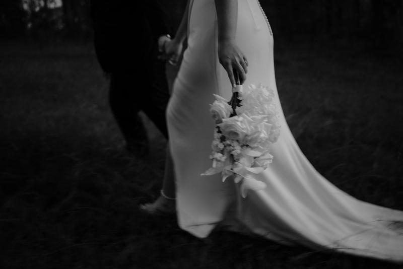 Nikki-Karen Willis Holmes-Bride holds flower bouquet in simple wrap wedding dress with long sleeves