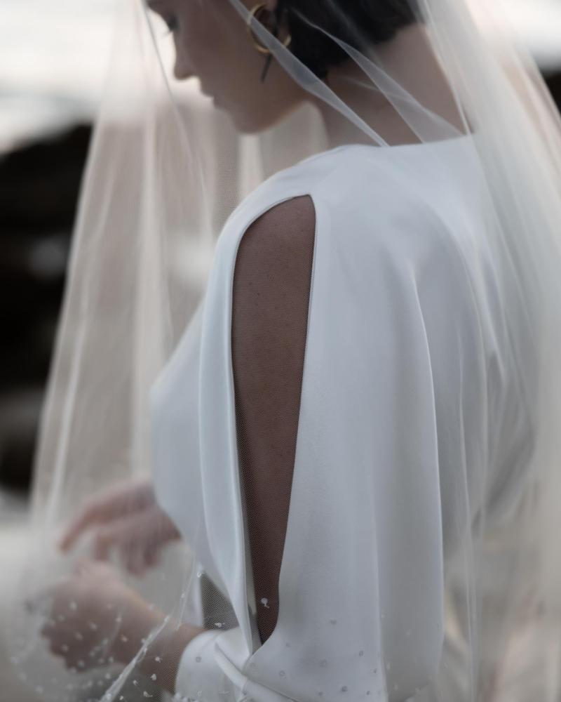 The Margo gown and Astra Veil by Karen Willis Holmes, a V-Neck, long sleeve silk satin wedding dress with a fit and flare shape and a split skirt.