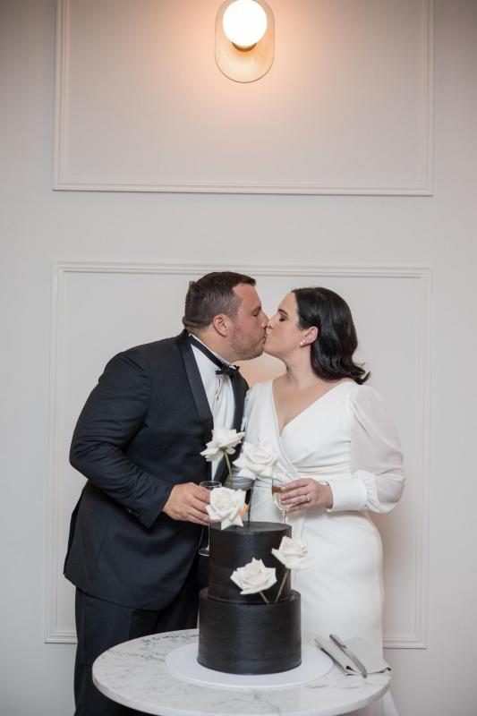 KWH real bride Dani kisses Thomas after the cake cutting. She wears the minimalist Nikki wedding dress