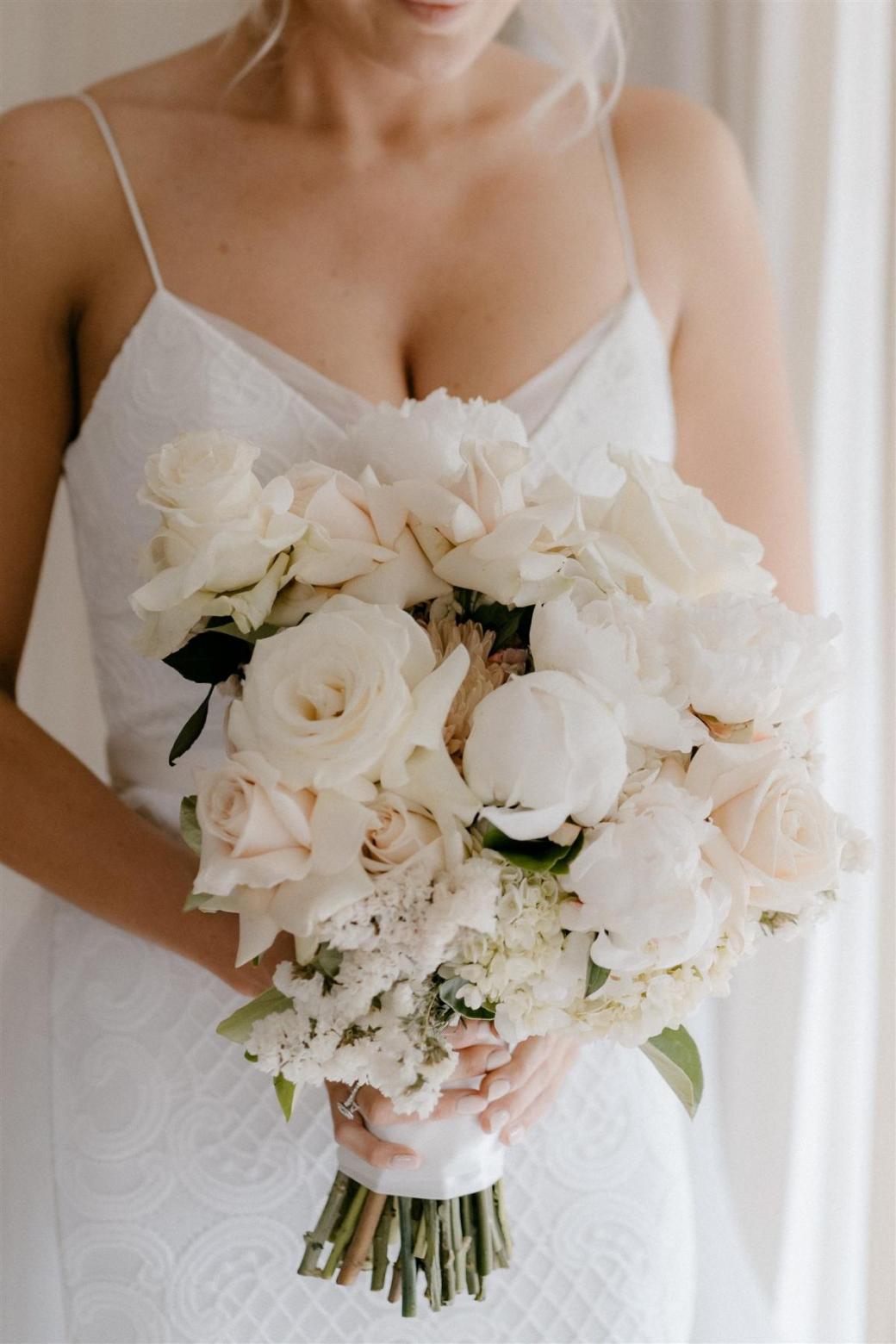 Bride in Elodie lace wedding dress by Karen Willis Holmes holding timeless bridal flowers