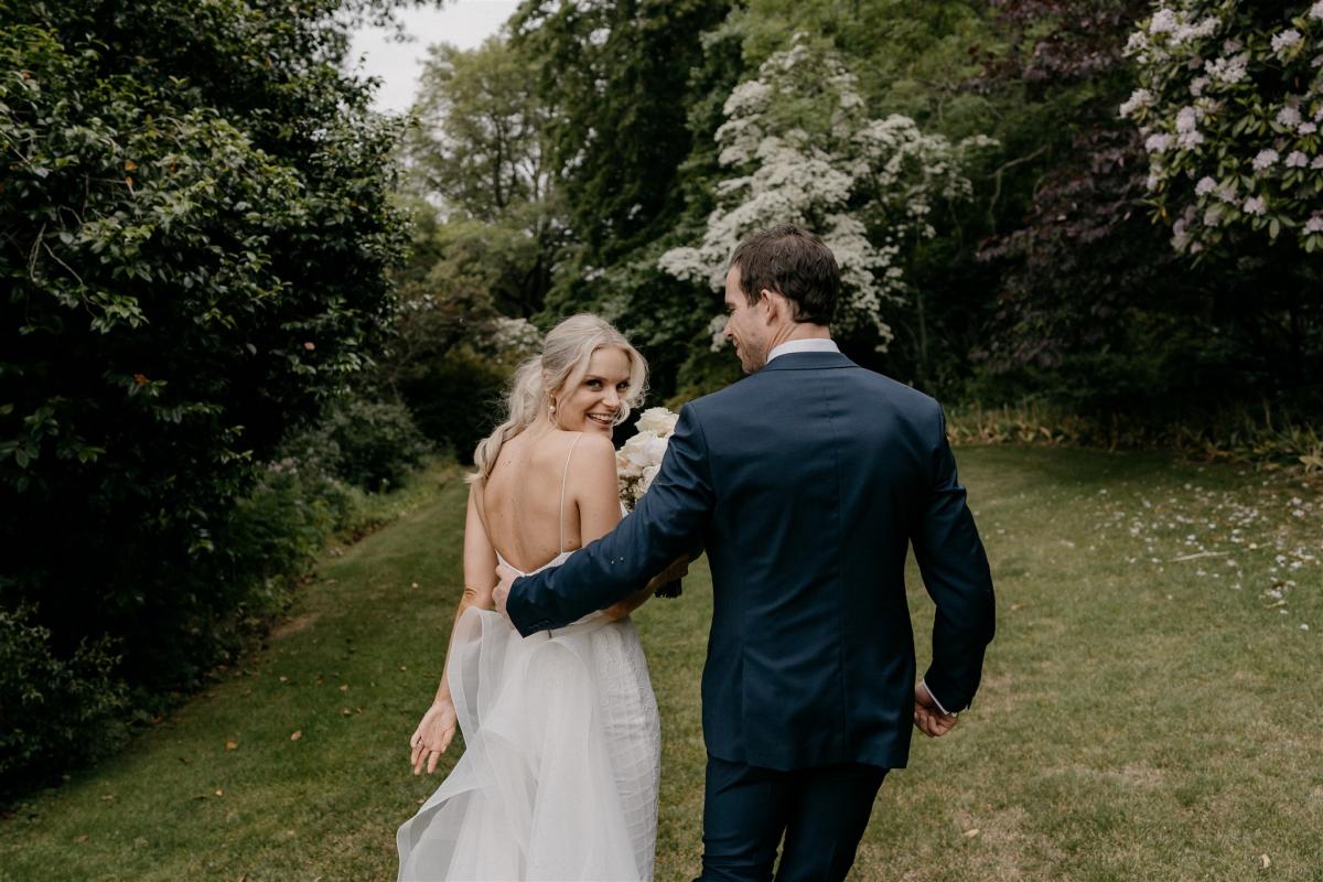 Couple portrait with bride looking behind shoulder in Karen Willis Holmes Elodie dress in garden