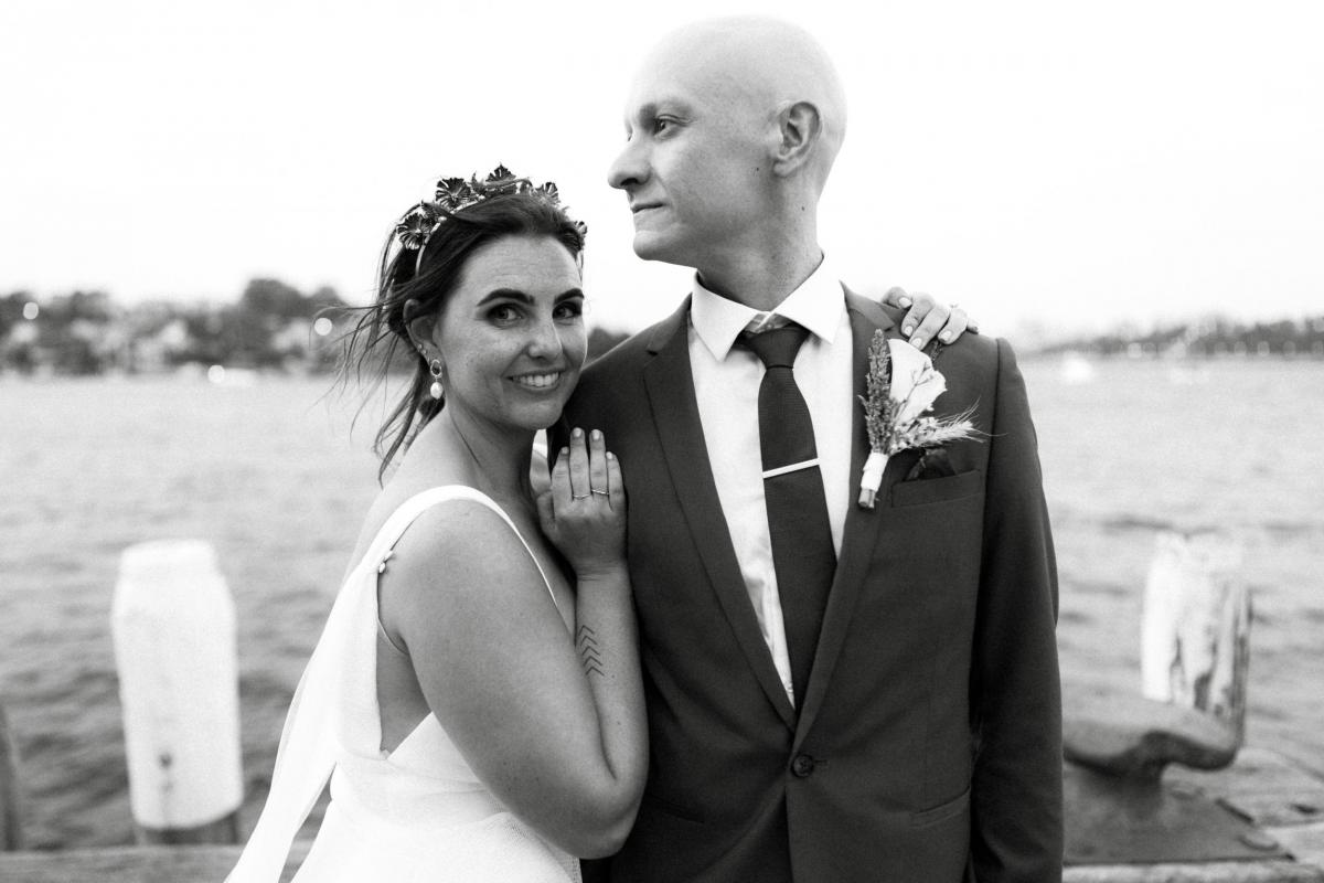 Bride and groom smiling in Sydney Harbour, bride wearing the Aisha gown by Karen Willis Holmes, a modern Bespoke wedding dress.