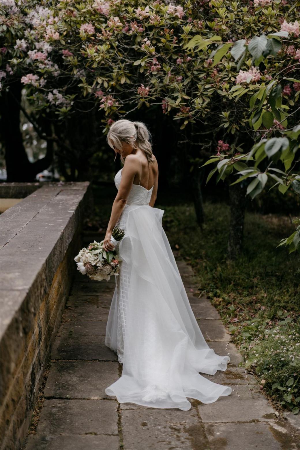 KWH bride Ashleigh and Adrian sharing a kiss at their country wedding; Ashleigh wears the dramatic Oval Trains with her Elodie gown by Karen Willis Holmes for ceremony look.