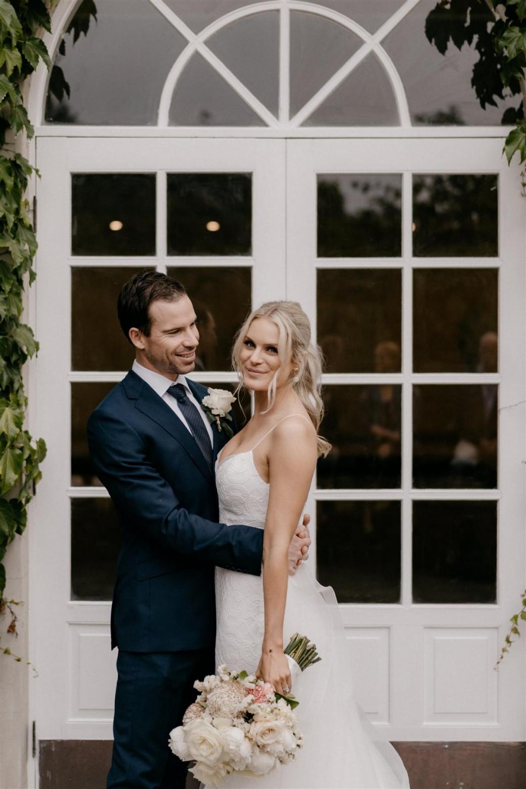 KWH bride Ashleigh and Adrian sharing a kiss at their country wedding; Ashleigh wears the dramatic Oval Trains with her Elodie gown by Karen Willis Holmes for ceremony look.