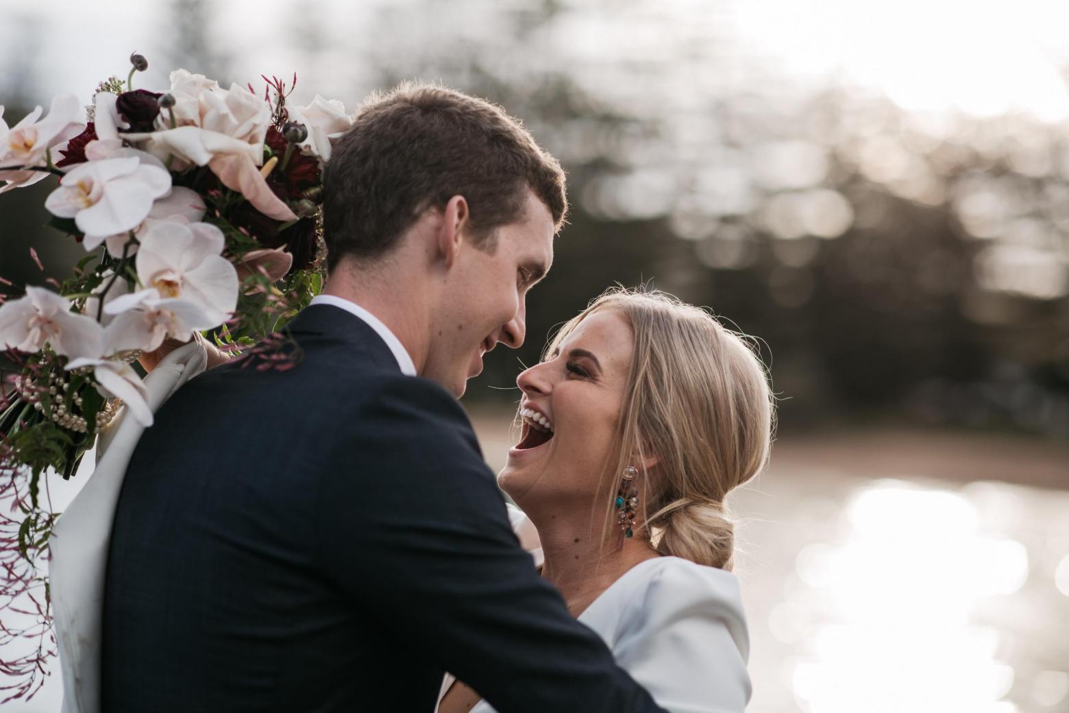 KWH bride Jordana celebrating with husband Mitch; holding her bridal bouquet.