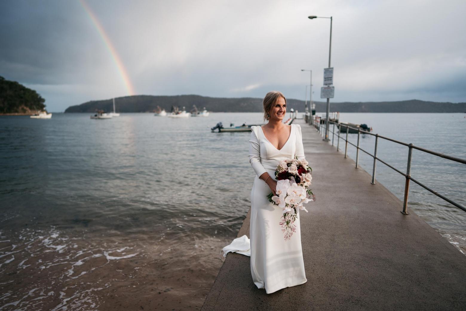 Bride Jordana under rainbow wearing the AUBREY gown by Karen Willis Holmes; featuring a V-neck and long-sleeves.