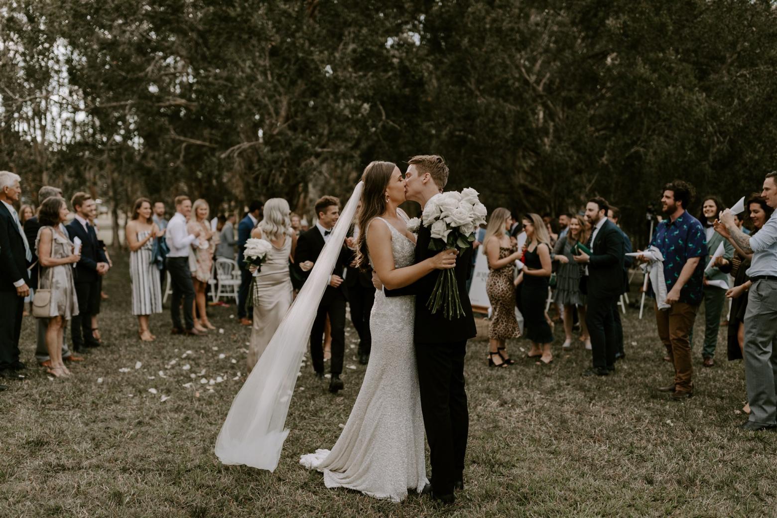 KWH couple just married at wedding ceremony; bride wearing sequin GEORGINA gown.