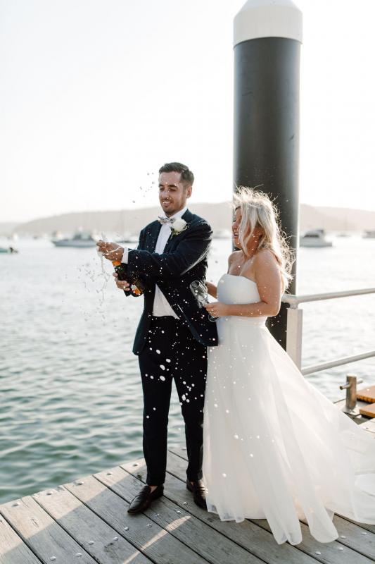 KWH bride Celeste & Daniel celebrating with champagne; wearing the Bespoke ESTHER gown, a modern ball-gown style wedding dress.