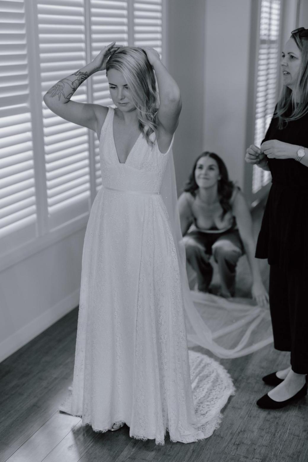 Karen Willis Holmes bride Megan getting ready with bridesmaids for romantic wedding, wearing the Nadia gown; an edgy and romantic lace wedding dress with a V-neck and side split.
